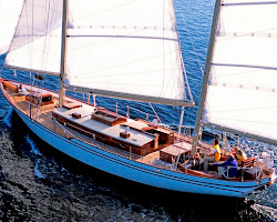 A ketch sailing boat with two masts cruising at sunset