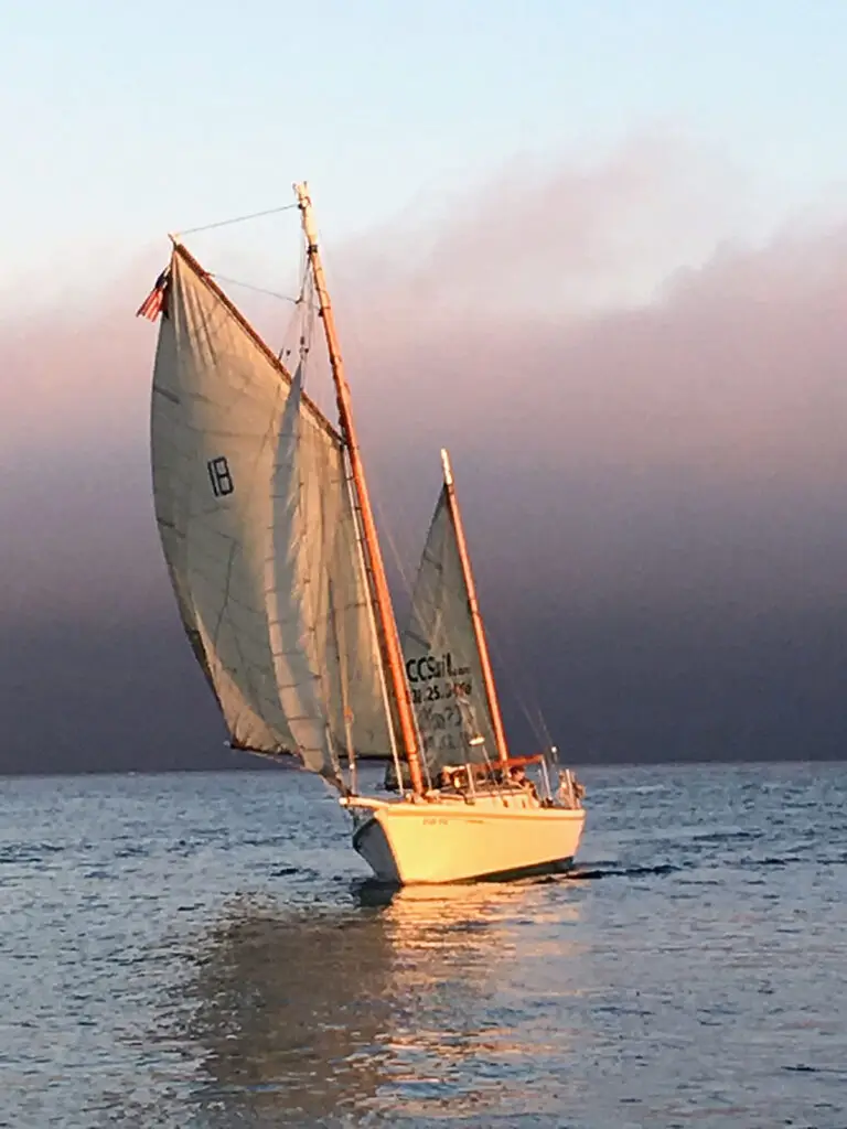 A classic gaff‑rigged yawl sailing offshore under clear skies.