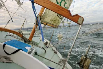 A sailboat heeling in the wind with rigging and boom visible on deck.