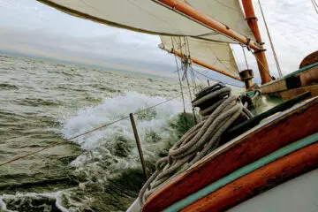 A sailboat heeling in the wind with rigging and boom visible on deck
